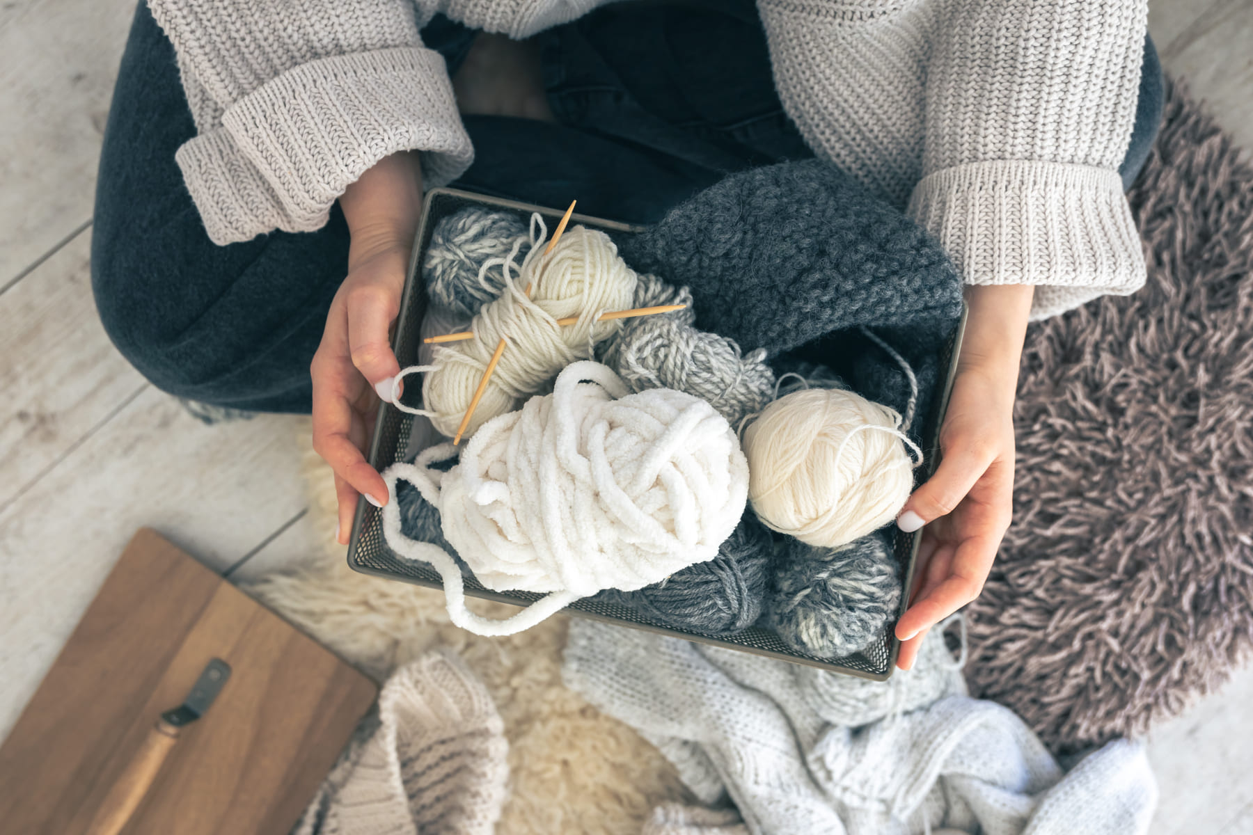 closeup-woman-hands-wearing-wool-sweater-holding-box-with-balls-thread (1) (1)